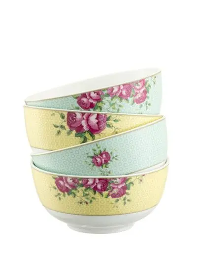 A stack of three ceramic bowls with floral patterns in pink and green, each featuring a different pastel background color. the bowls are set against a white background.